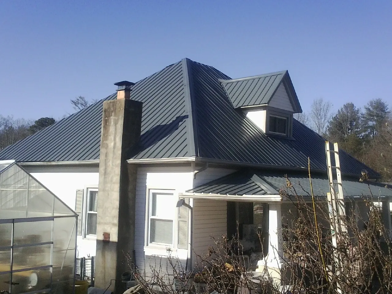 Dark blue standing seam metal roof on a white farmhouse with dormer — Slate & Tile Roof Repair by Roofing Brothers in Collegedale