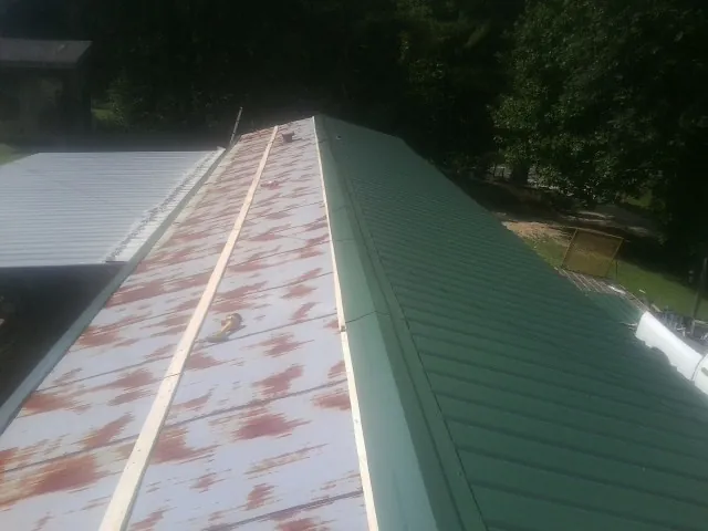 Old rusted panels beside newly installed green metal roofing — Wind Damage Roof Repair by Roofing Brothers in Collegedale