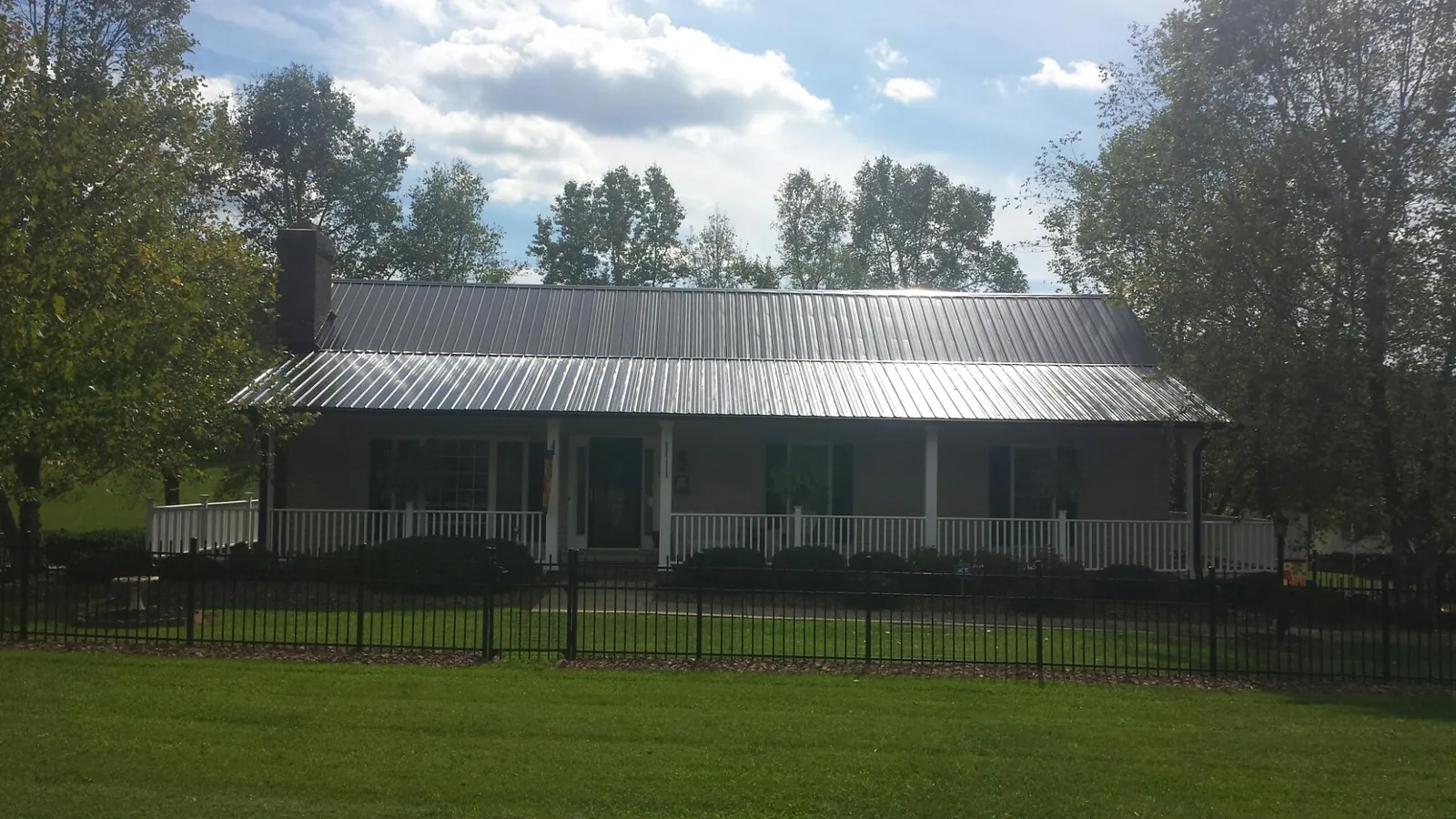 Gray metal roof on a brick ranch with a full width front porch — Gutter Guard Installation work by our crew in Collegedale