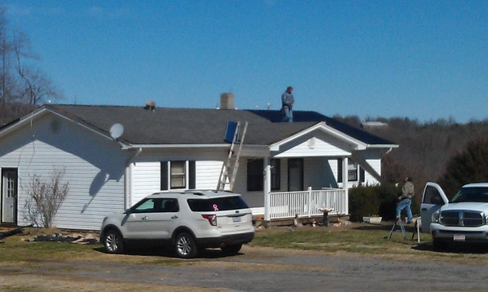Roofers stripping shingles from a white ranch house roof in Collegedale