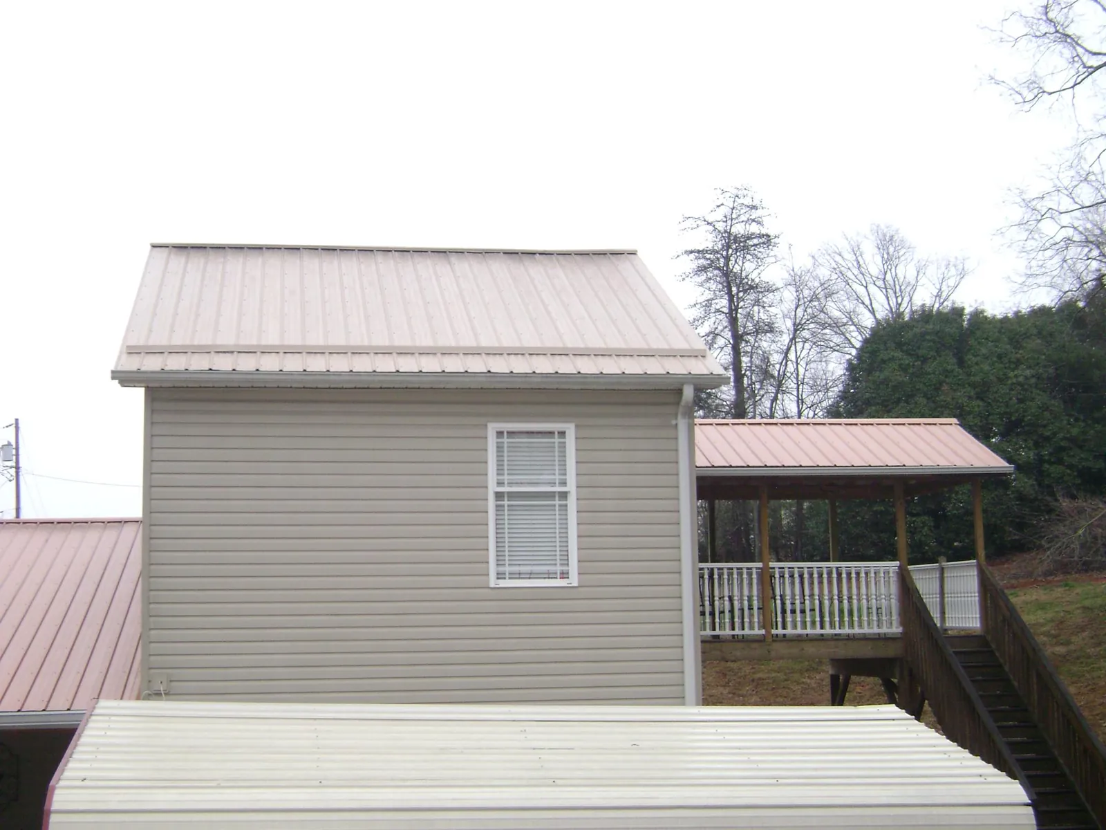 Tan metal roofs on a two story addition and attached porch, from a Roof Replacement job in Collegedale