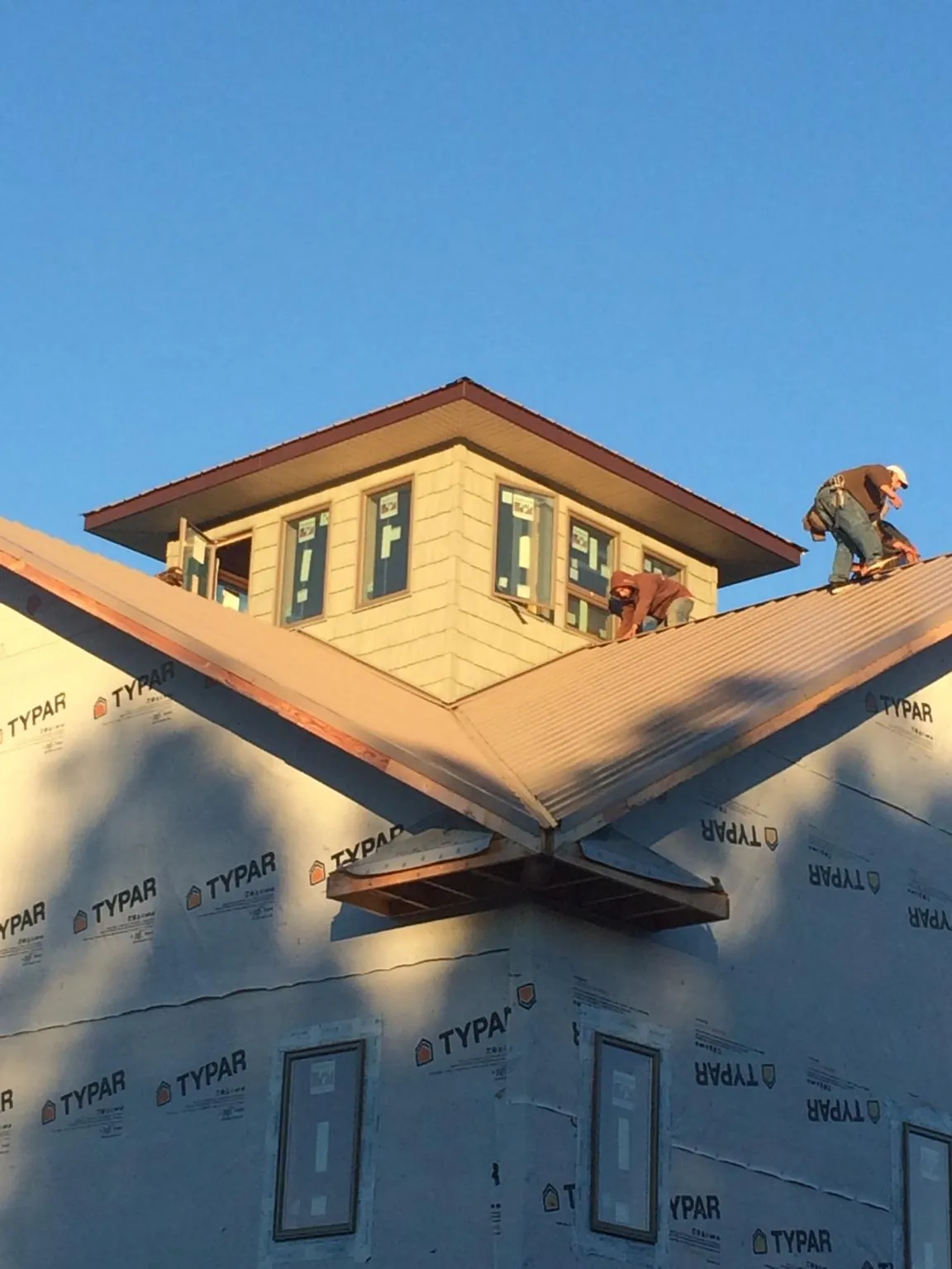 Roofers working around a rooftop cupola on a new metal roof at sunset — Roof Waterproofing in Collegedale by Roofing Brothers